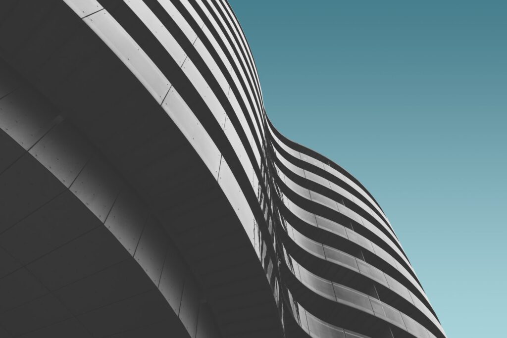 The curved, striped facade of a building against a teal sky